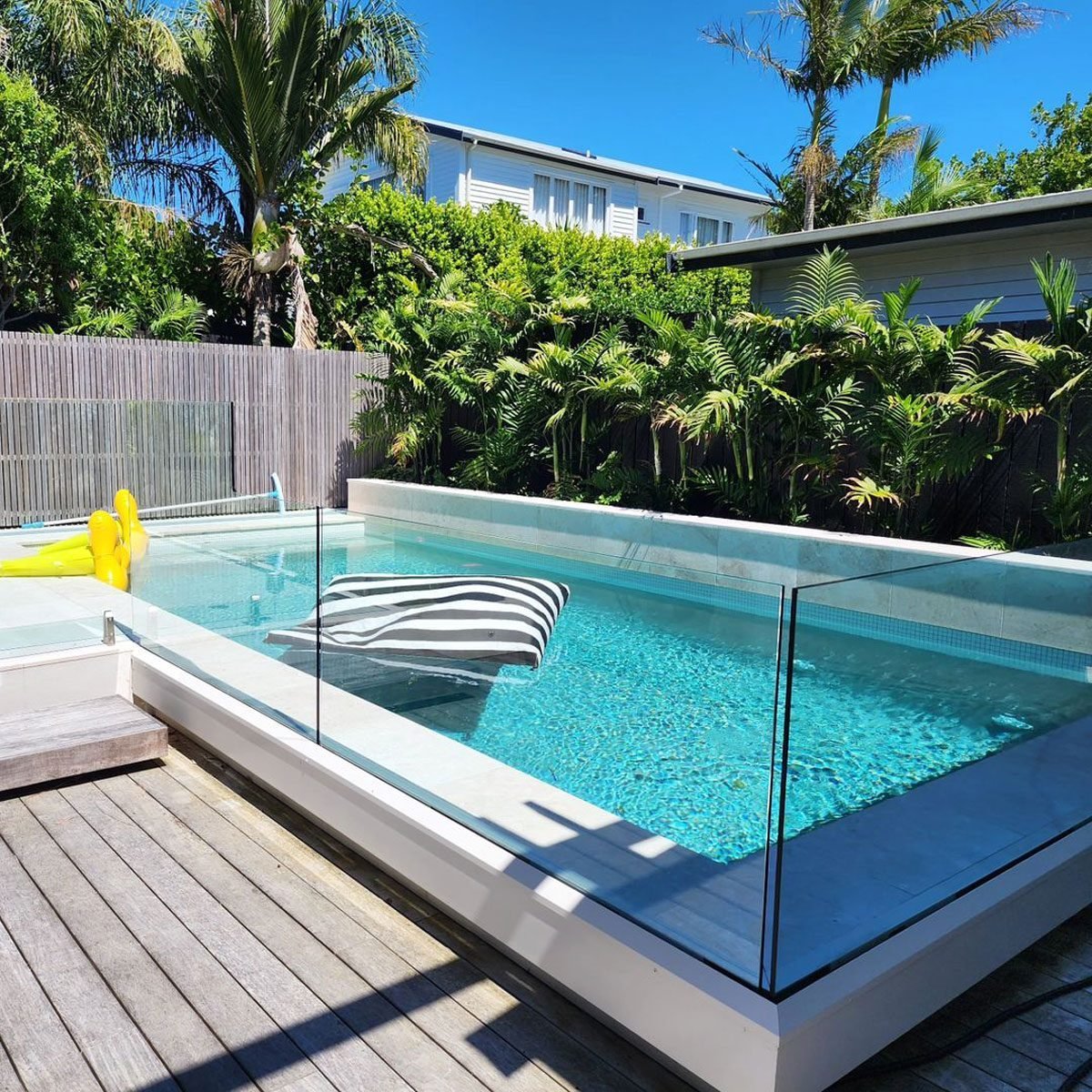 Modern glass pool fencing around backyard swimming pool